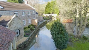 A narrow canal flanked by stone buildings with a wooden shed and a clock. - 3 bedroom accommodation in Spring Gardens, Frome (Spring Gardens, Frome)