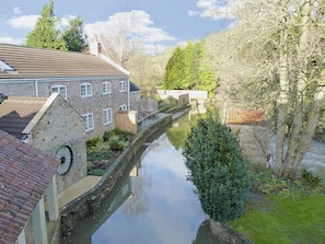 A narrow canal flanked by stone buildings with a wooden shed and a clock. - 3 bedroom accommodation in Spring Gardens, Frome (Spring Gardens, Frome)