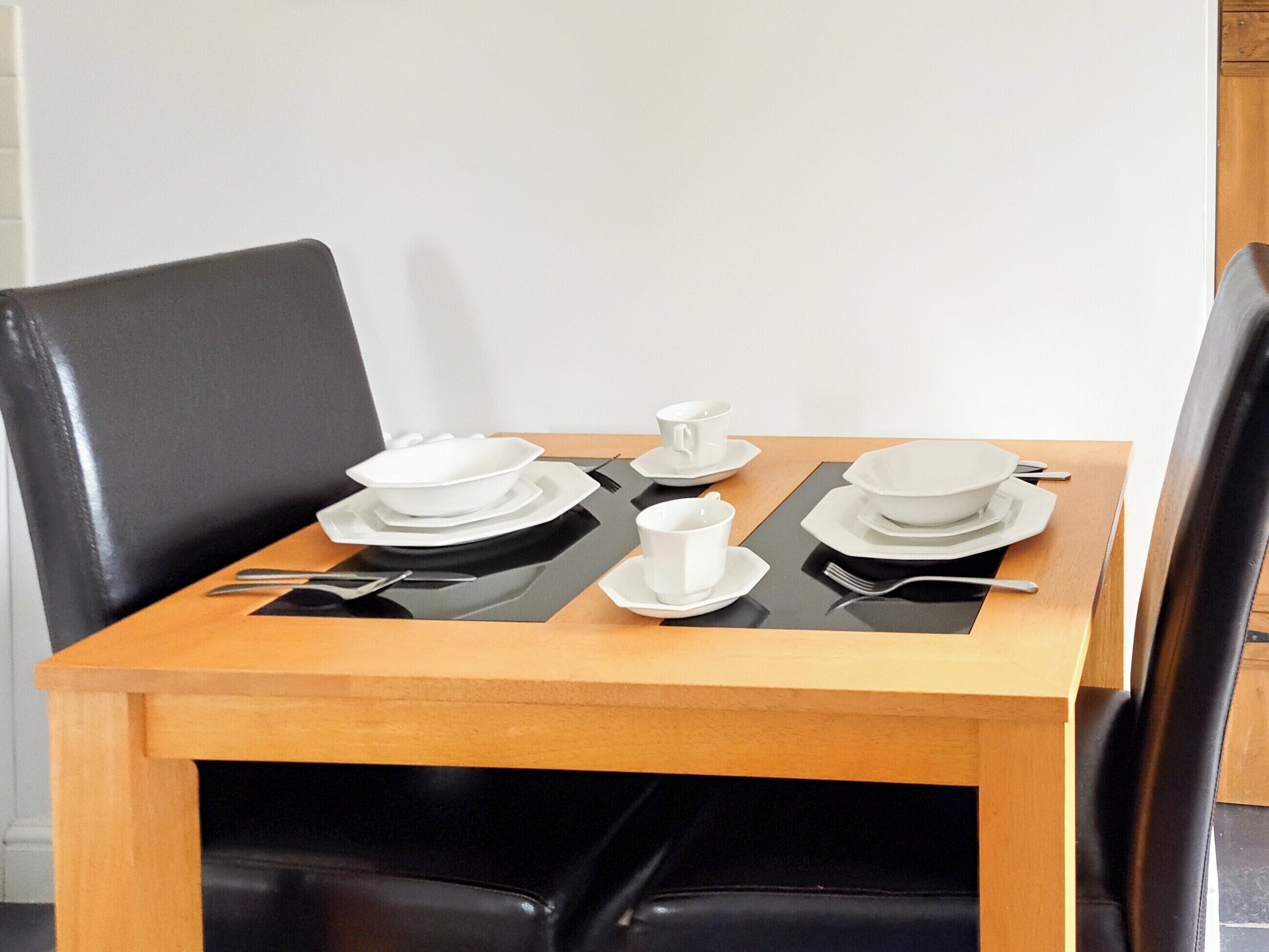 A dining table with white plates, bowls, and cutlery.