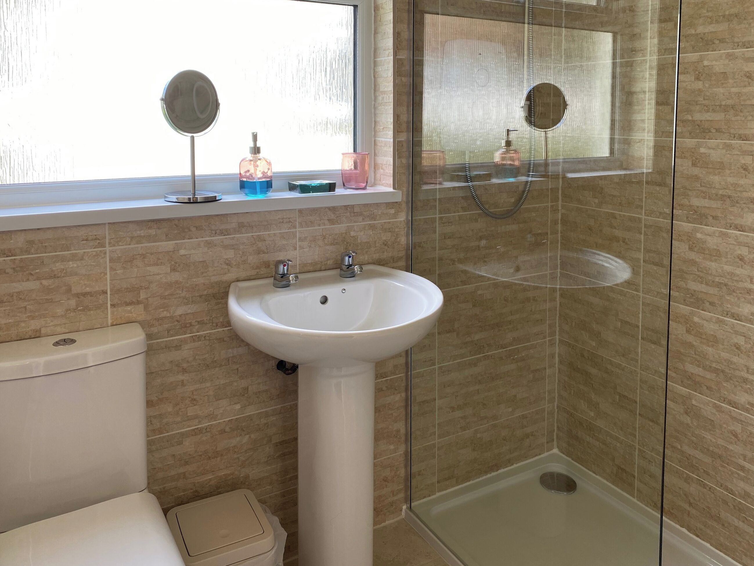 Ein Badezimmer mit einem Standwaschbecken, einer Toilette und einer Duschkabine.