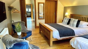 A bedroom with a bed, a chair, a desk, and a mirror.