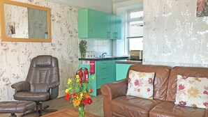 A living room with a brown leather sofa, a wooden coffee table, a brown leather armchair, and a vase of flowers. - Old Barn Farm Cottage - CC539048 (Uplawmoor, near Paisley)