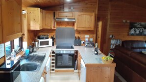 A compact kitchen with wooden cabinets, a microwave, a toaster, and a sink. - Ewe How - Burnside Park (Keswick)