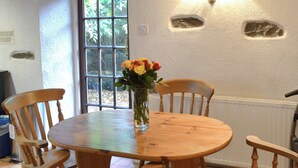 Ein Holztisch mit Stühlen, eine Vase mit Blumen und ein Fenster mit Blick ins Grüne.