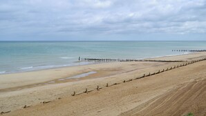 Ein weiter Sandstrand mit einer hölzernen Steg, der sich ins Wasser erstreckt.
