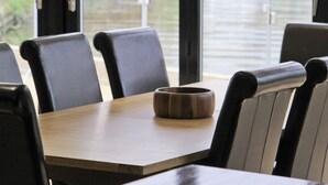 Ein Restaurant mit Holztisch und schwarzen Stühlen, mit Blick auf ein Gewässer mit Booten.