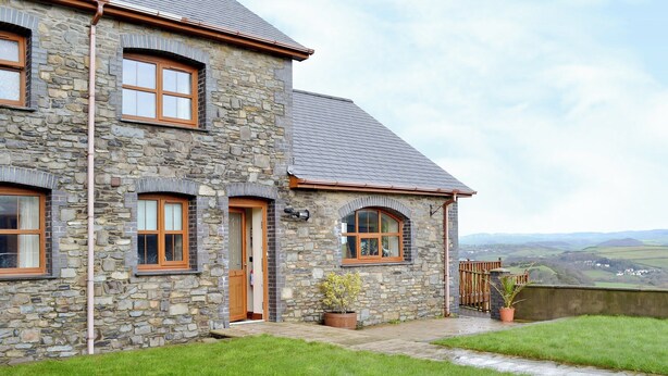 Une maison en pierre avec un toit gris, une porte en bois et un petit jardin.