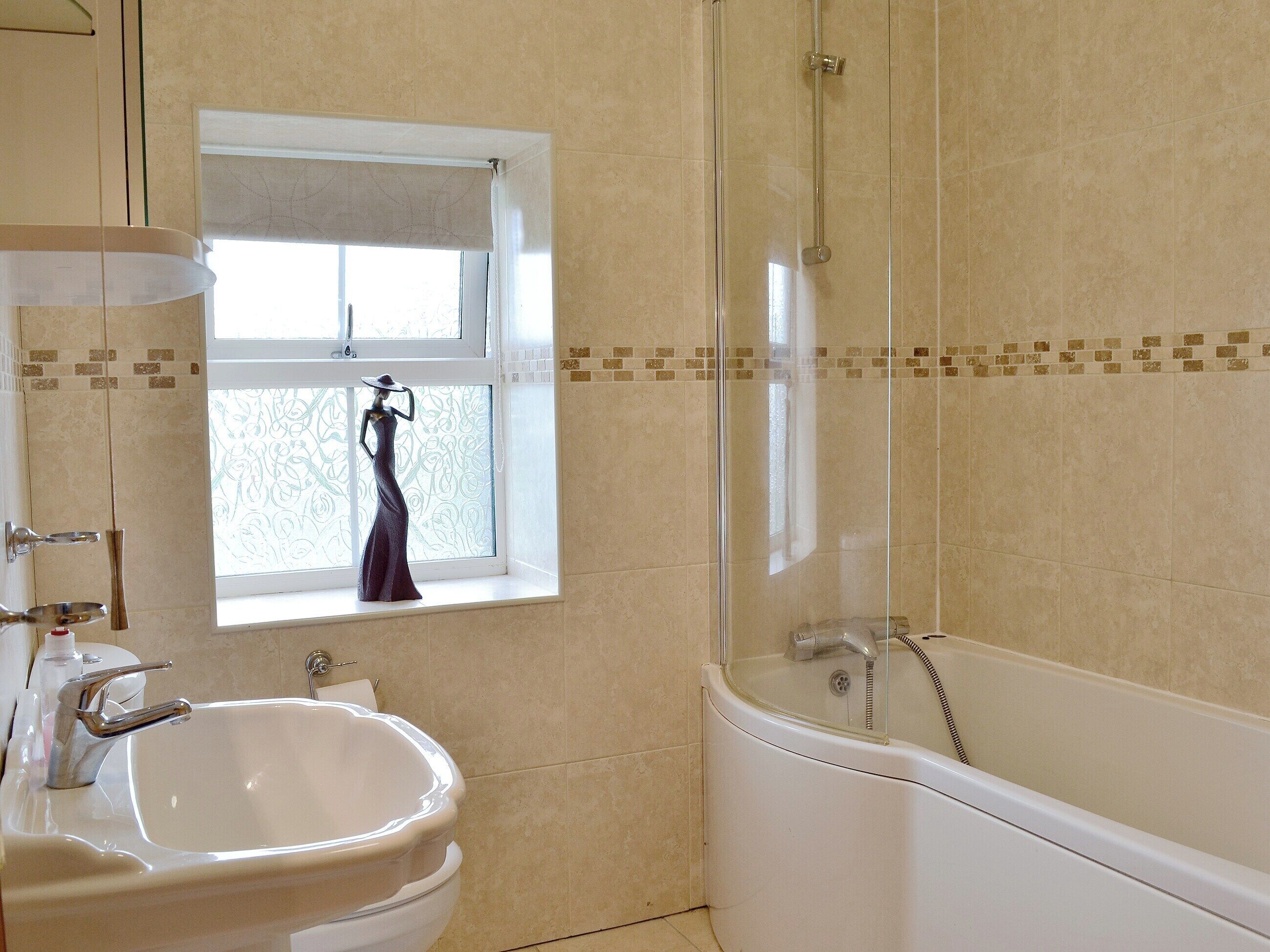 A bathroom with a bathtub, a sink, and a window with a decorative item.
