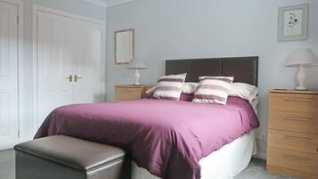 A bedroom with a bed, bedside tables, a bench, a dresser, and a mirror.