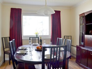 A dining room with a round table, chairs, a chandelier, and a cabinet. - 4 bedroom accommodation in Carrbridge (Carrbridge)