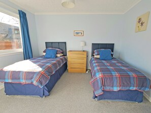 A bedroom with two beds, a dresser, a window with curtains, and a framed picture on the wall. - 4 bedroom accommodation in Carrbridge (Carrbridge)