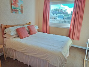 A neatly made bed with white and pink bedding, a wooden headboard, and a painting on the wall. - 4 bedroom accommodation in Carrbridge (Carrbridge)