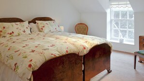 Un dormitorio con cama, una silla, una ventana y una lámpara en el techo.