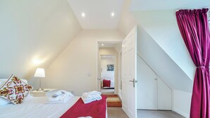 A bedroom with a bed, a nightstand, a lamp, and a door leading to a hallway. - 2 bedroom accommodation in Stirling (Stirling)