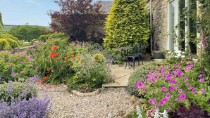 Un giardino con diversi fiori e un muro in pietra.