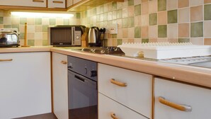 A kitchen with white cabinets, a microwave, a kettle, and a toaster. - 2 bedroom accommodation in Ambleside (Ambleside)