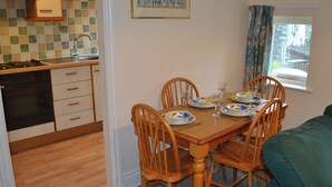 A compact kitchen with a dining area, wooden chairs, and a table set for two. - 2 bedroom accommodation in Ambleside (Ambleside)