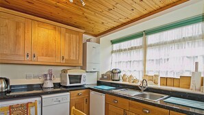 A kitchen with wooden cabinets, a microwave, a coffee maker, and a sink. - 2 bedroom accommodation in Birnam, near Dunkeld (Birnam, near Dunkeld)