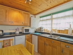 A kitchen with wooden cabinets, a microwave, a coffee maker, and a sink. - 2 bedroom accommodation in Birnam, near Dunkeld (Birnam, near Dunkeld)