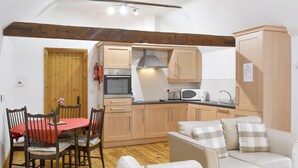Une cuisine de taille réduite avec des meubles en bois, une table à manger avec des chaises et un canapé.