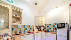 A compact kitchen with white cabinets, a microwave, a coffee maker, and a sink.