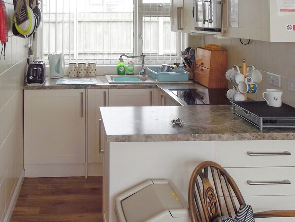 A kitchen with a sink, countertop, and cabinets. There are utensils and a coffee maker on the counter. - 2 bedroom accommodation in Walcott (Walcott)