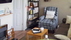A living room with a sofa, a chair, a coffee table, a bookshelf, and a television.