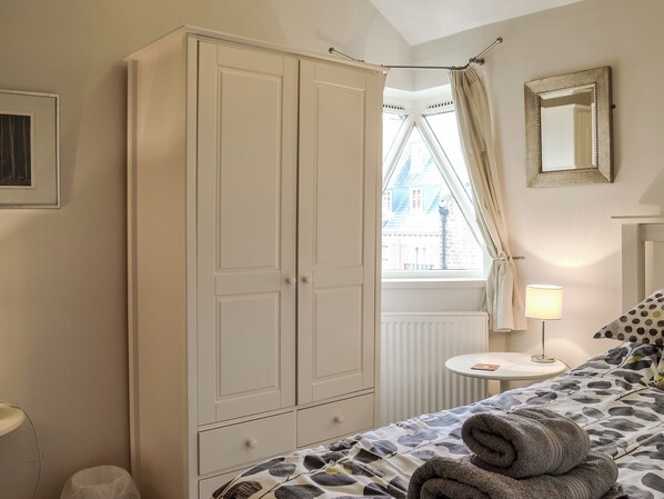 A bedroom with a bed, a bedside table with a lamp, a window with curtains, and a wardrobe. - 2 bedroom accommodation in York (York)