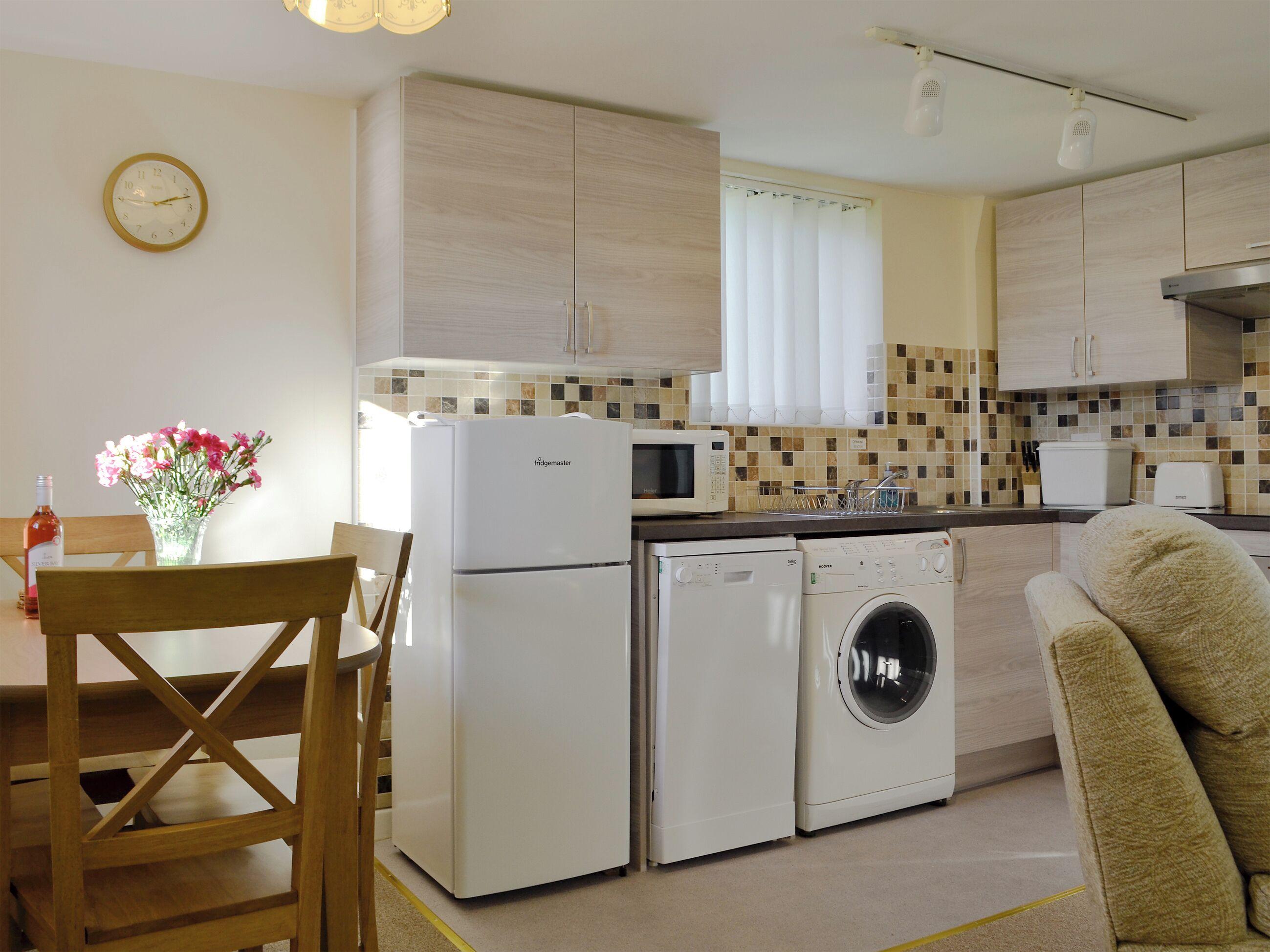 Cocina compacta con refrigerador, microondas, lavadora y comedor con una silla y mesa.