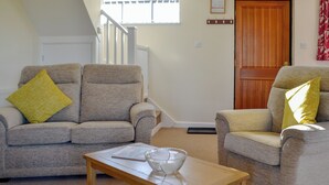 A living room with two grey armchairs, a wooden coffee table, and a window with a view of a staircase. - Sally's Nest - E3042 (Wenhaston, near Southwold)