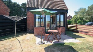A small brick house with a tiled roof, a glass door, and a patio with a table and chairs. - Sally's Nest - E3042 (Wenhaston, near Southwold)