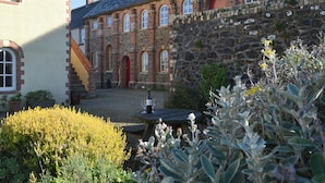 A historic building with a stone facade, arched windows, and a red door.