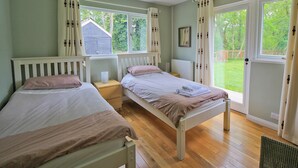 Une chambre avec deux lits, une fenêtre et une porte donnant sur un jardin.