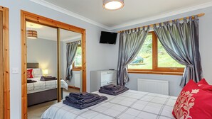 A bedroom with a bed, a TV, a radiator, and a window with curtains. - 1 bedroom accommodation in Achaphubuil near Fort William (Achaphubuil near Fort William)