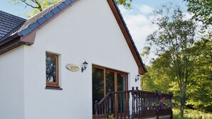A white building with a brown roof, a wooden staircase, and a sign that reads "Carinish Beag." - 1 bedroom accommodation in Achaphubuil near Fort William (Achaphubuil near Fort William)