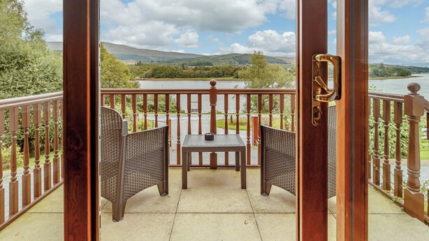 A balcony with wicker furniture and a view of a lake and hills. - 1 bedroom accommodation in Achaphubuil near Fort William (Achaphubuil near Fort William)