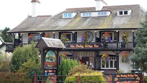 Pooley Bridge Inn, en traditionel bygning med balkon, blomsterkasser og et skilt, der angiver, at det er et værtshus med 4 kanaler i alle værelser.