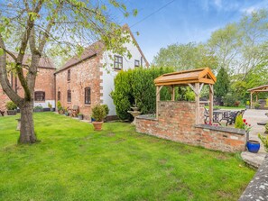 A brick building with a white facade, a wooden pergola, and a well-maintained lawn. - 3 bedroom accommodation in York (York)
