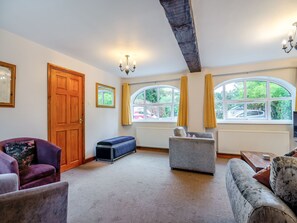 Un salón amplio con techo alto, ventanas grandes y una zona de estar acogedora.