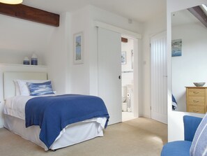 A bedroom with a bed, a dresser, a chair, and a door leading to a bathroom.