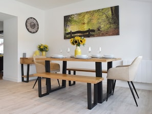 Un coin repas avec une table en bois, des bancs et un tableau représentant une scène de forêt.