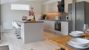 Eine moderne Küche mit einer zentralen Kochinsel, Edelstahlgeräten und einem Essbereich mit Holztisch.