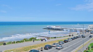 Una strada costiera con un molo che si protende verso il mare, accanto a una spiaggia.
