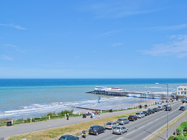 Eine Küstenstraße mit einem Steg, der sich ins Meer erstreckt, neben einem Strand.