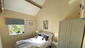 Une chambre à coucher comprenant un lit, des tables de chevet, une armoire, une fenêtre avec vue et des œuvres d’art accrochées aux murs.
