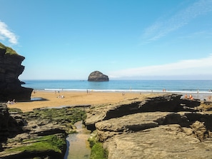 A coastal beach with rocky formations and clear blue water.