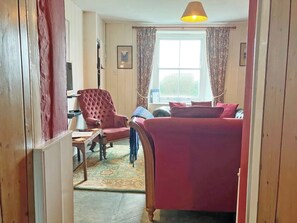 A room with a bed, a chair, a table, and a window with curtains.