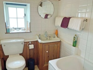 Une salle de bain comprenant des toilettes, un lavabo, un miroir et une baignoire.