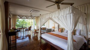 Un dormitorio amplio con una cama grande, ventilador de techo y vistas al exterior.