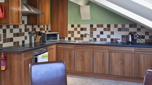 A kitchen with wooden cabinets, a microwave, a sink, and a fire extinguisher.